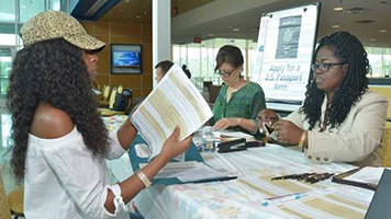 Albany State University student Cauntillia Pollard, left, submits documents to a U.S. Postal Service passport agent during a recent “Passport Caravan.”